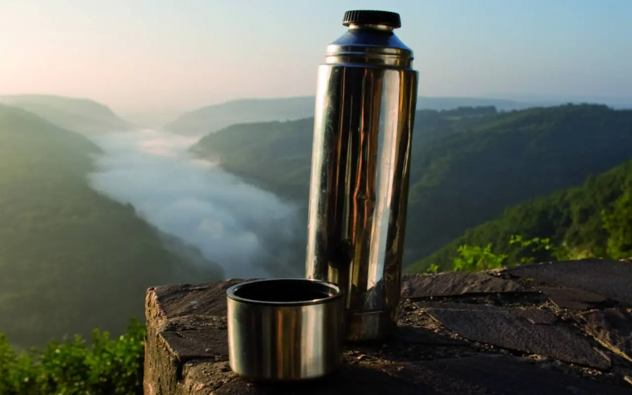 Thermoskanne und Tasse mit Blick auf die nebelverhangene Saarschleife bei Sonnenaufgang, nahe Buchnas Landhotel.