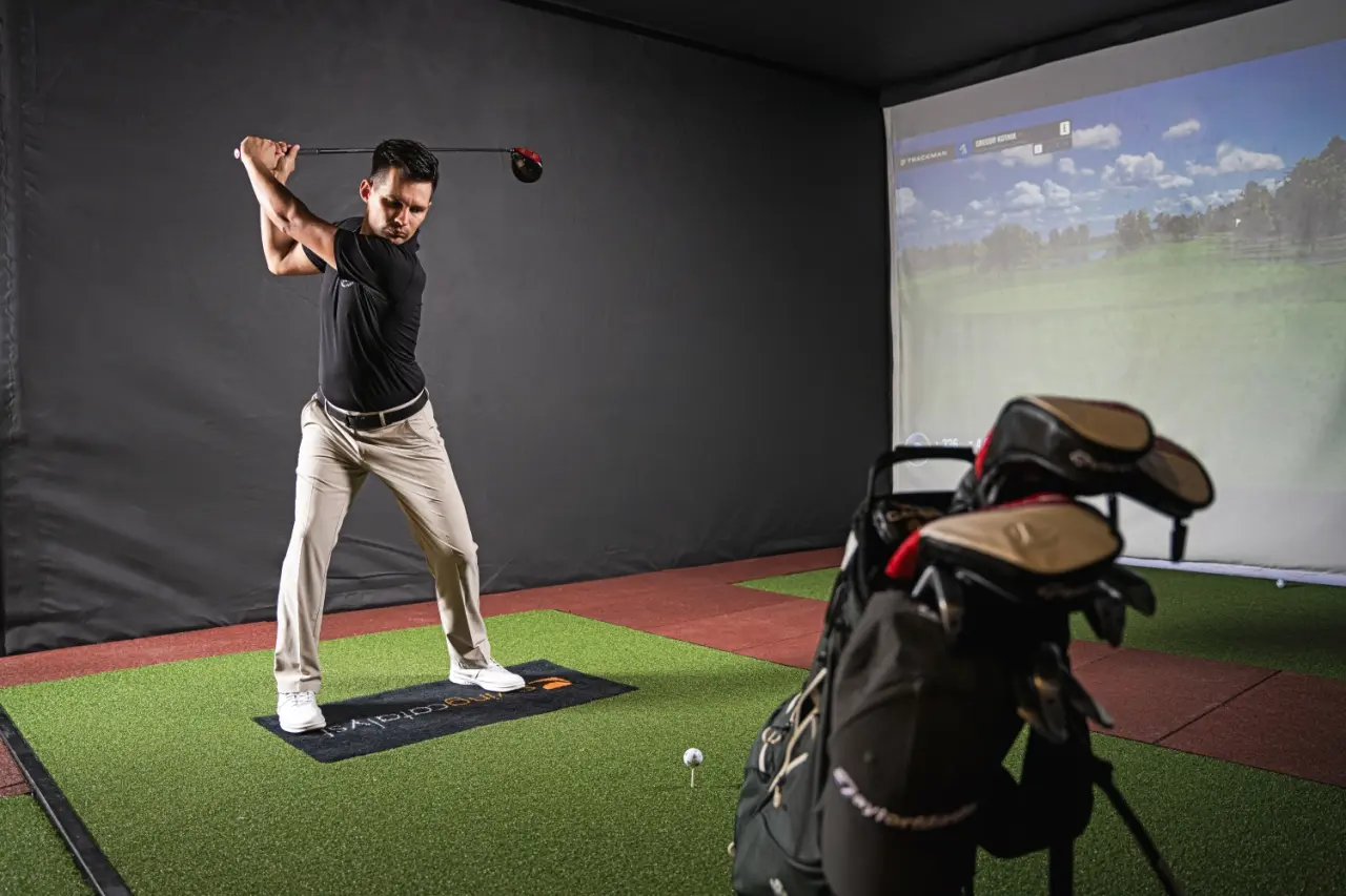 Mann beim Golfschwung im Indoor-Golfsimulator des IMLAUER Hotel Schloss Pichlarn. Perfektioniere dein Spiel.