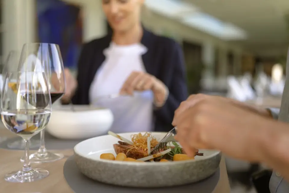 Gourmet-Mahlzeit mit Wein im Restaurant des IMLAUER Hotel Schloss Pichlarn. Gäste genießen exzellente Küche.