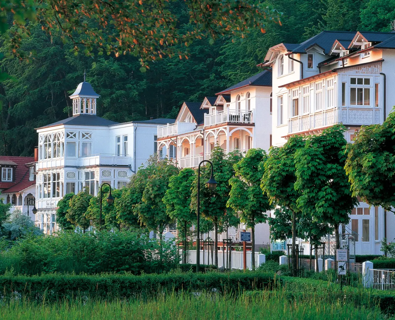 Elegante Bäderarchitektur des Hotel Vier Jahreszeiten Binz an der Ostsee, umgeben von grünen Bäumen und Natur.
