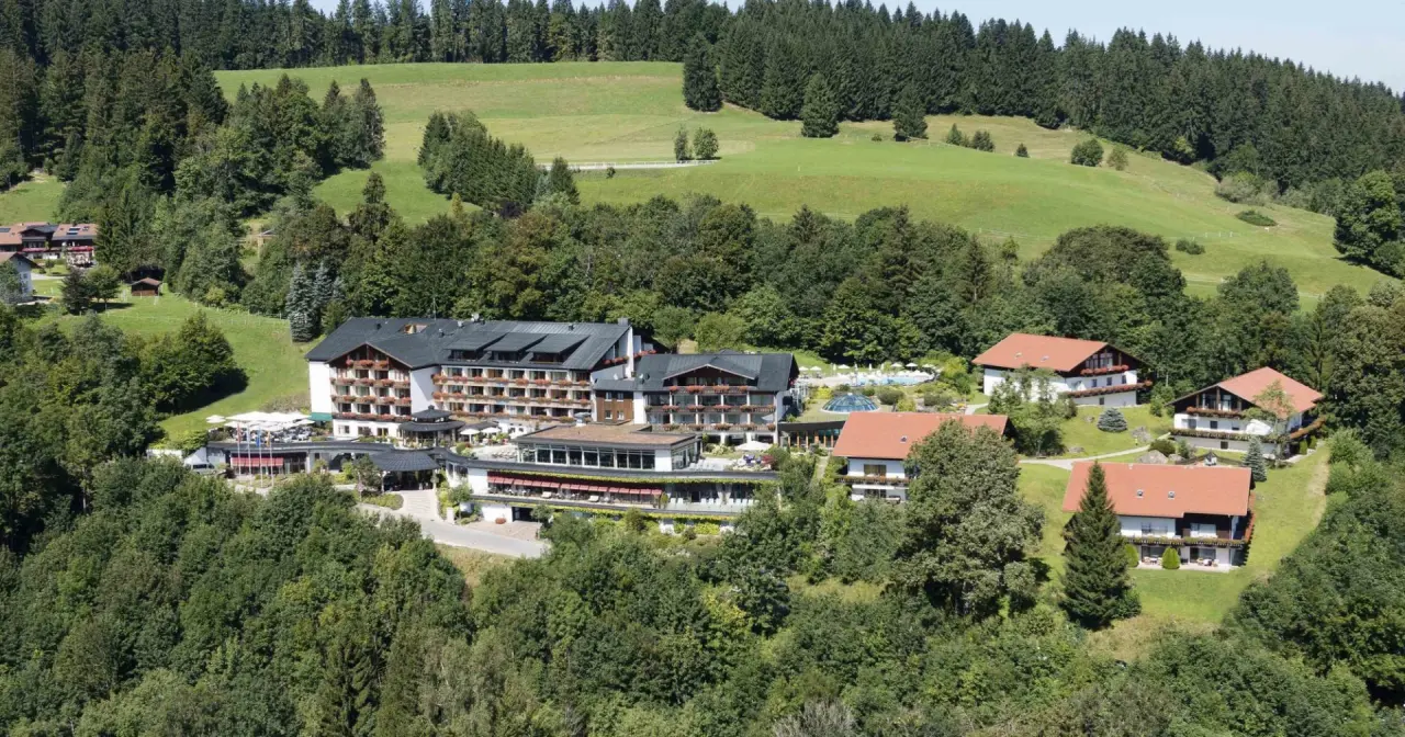 Luftaufnahme des 5* Sport- & Wellnesshotel Allgäu Sonne, eingebettet in grüne Hügel und Wälder.
