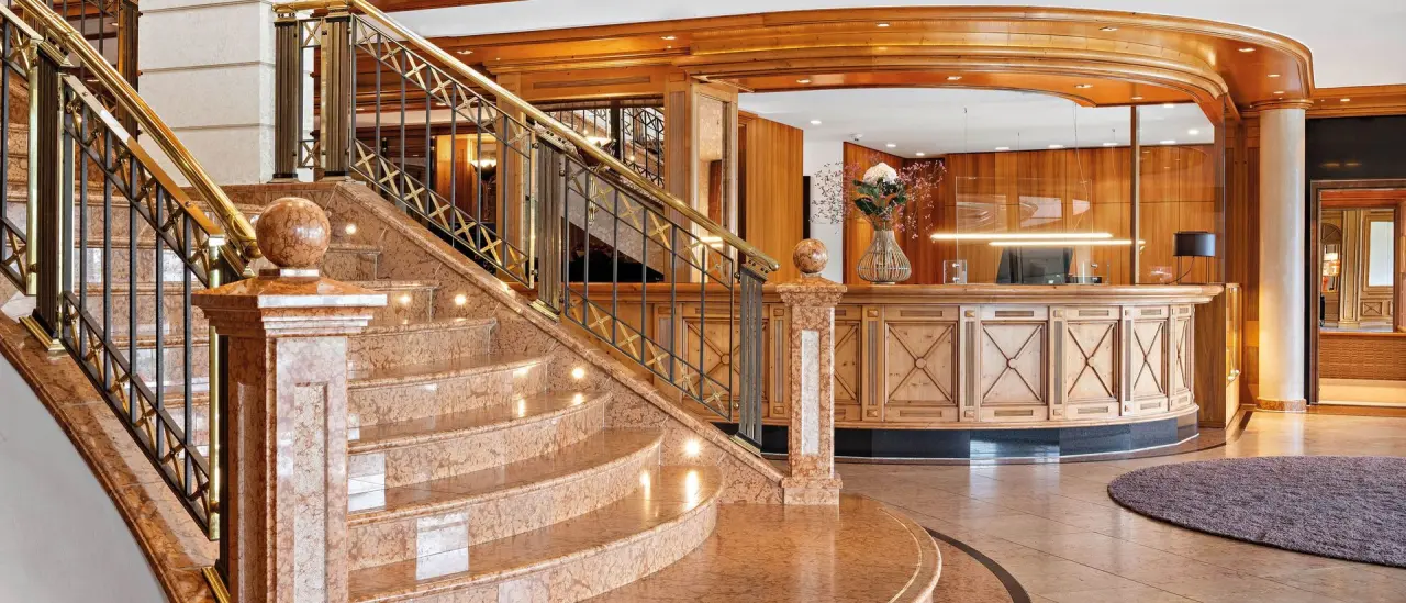 Elegante Lobby mit Marmortreppe und Rezeption im 5* Sport- & Wellnesshotel Allgäu Sonne.