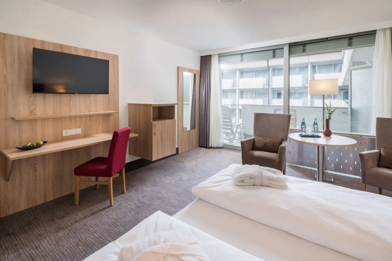 Komfortables Hotelzimmer im Hotel Frankenland mit Doppelbett, Schreibtisch, Sitzbereich und Balkon.