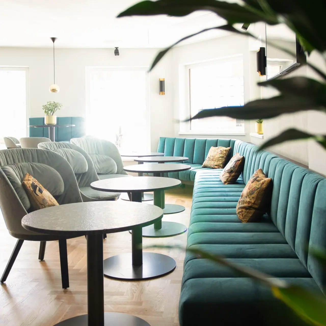 Moderne Lounge mit teal-farbenen Sitzbänken und bequemen Sesseln im Alpine Hideaway Zillertalerhof.