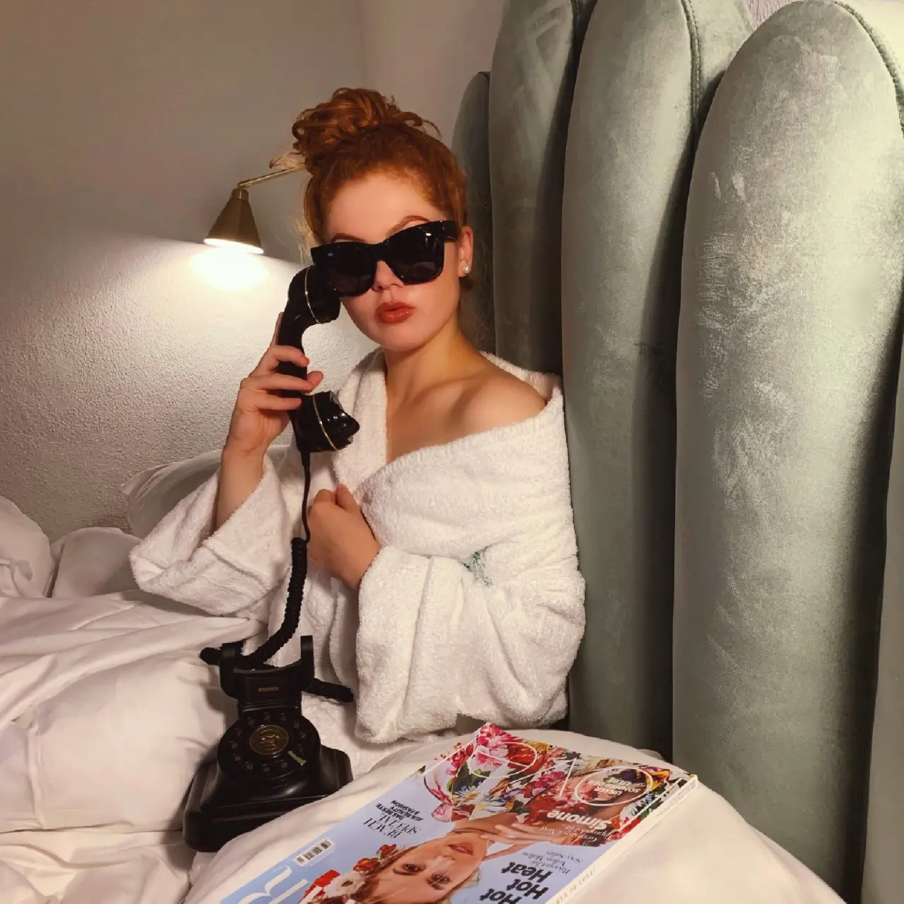 Entspannung im Hotelzimmer des Alpine Hideaway Zillertalerhof: Frau im Bademantel mit Retro-Telefon und Magazin.