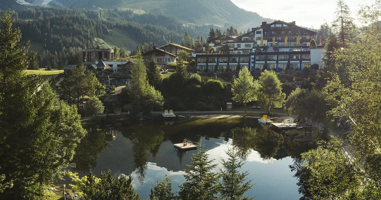 Panoramablick auf das Übergossene Alm Resort mit Natursee und Bergkulisse, ideal für Wellness und Entspannung.
