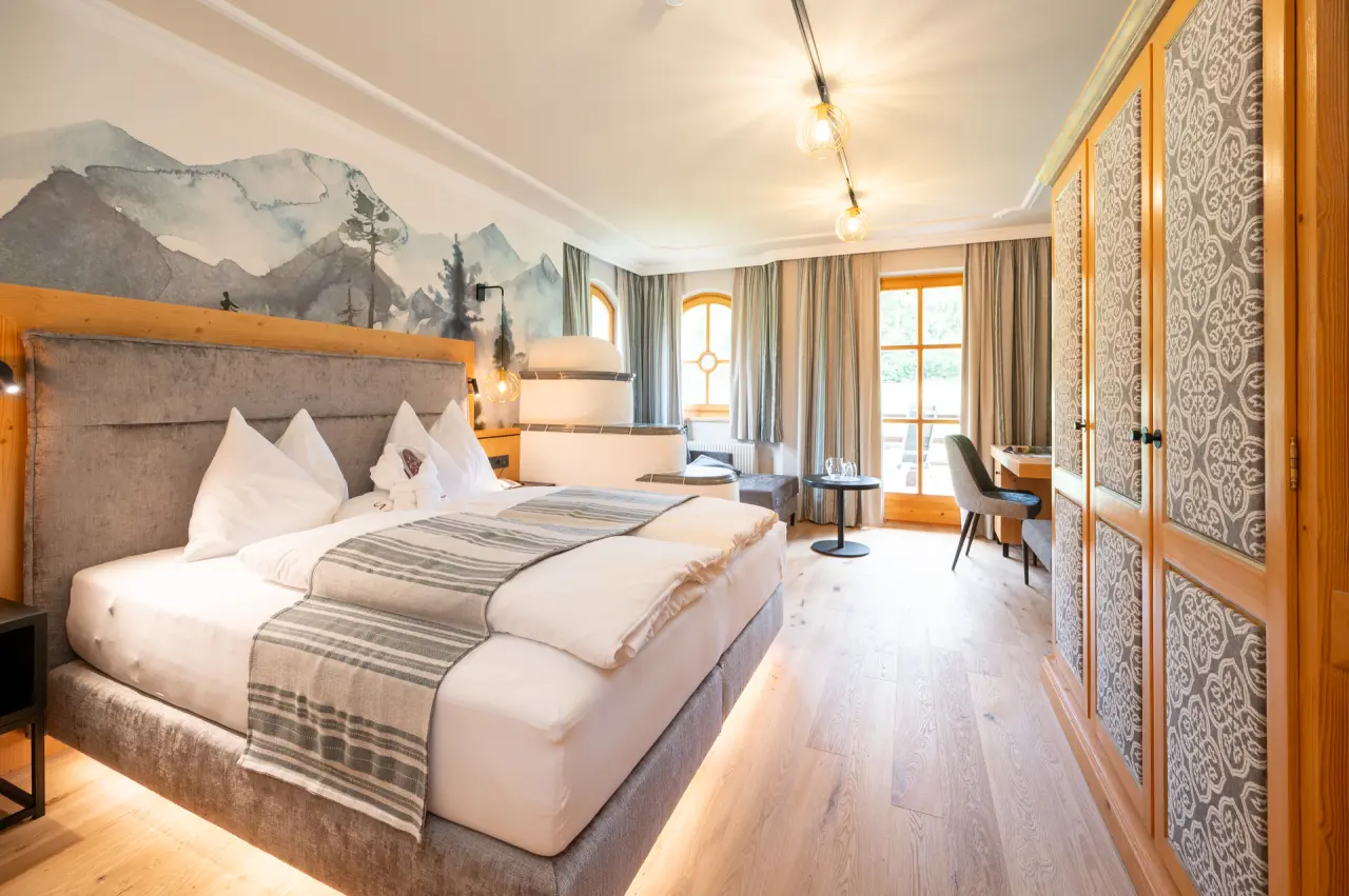 Komfortables Doppelzimmer mit modernem Design, Bergblick-Wandmalerei und Holzboden im Übergossene Alm Resort.