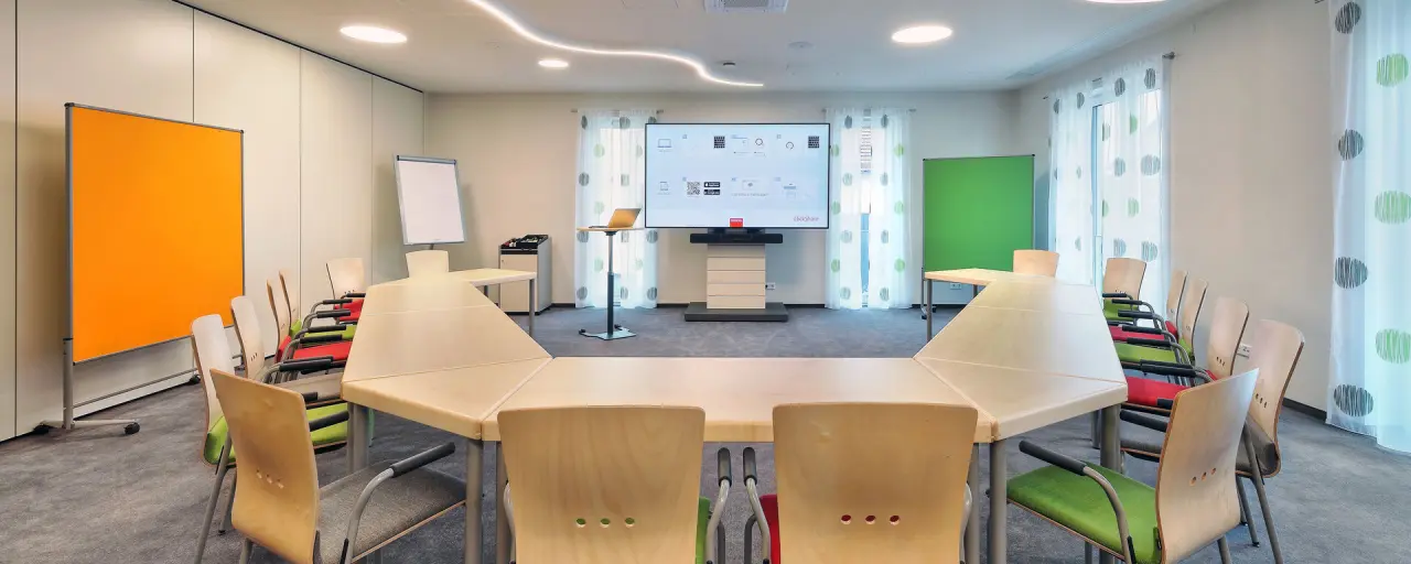Modern ausgestatteter Konferenzraum im Landhotel Geyer mit großem Bildschirm und flexiblen Tischen.