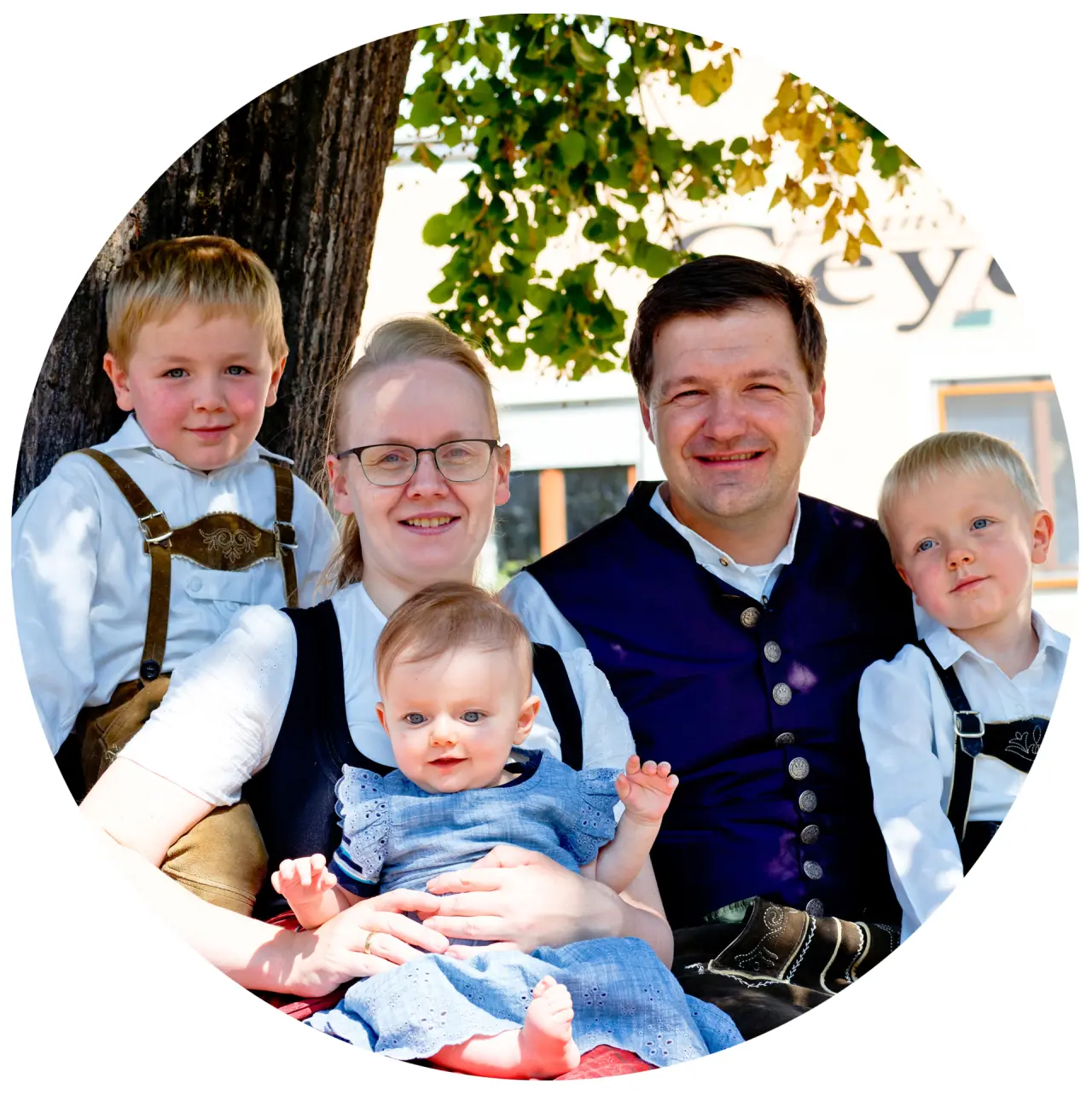 Lachende Familie Geyer in bayerischer Tracht vor dem Landhotel Geyer, symbolisiert Gastfreundschaft.
