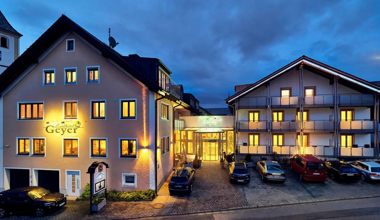 Aussenansicht des Landhotel Geyer bei Abenddämmerung mit beleuchteten Fenstern und einladendem Eingangsbereich.
