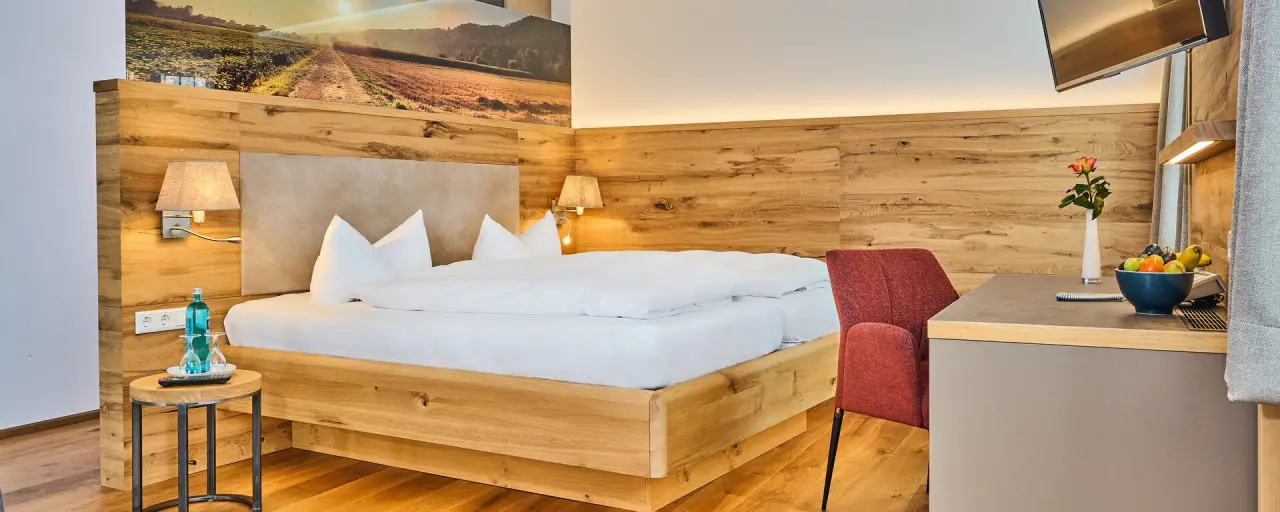 Komfortables Doppelzimmer im Landhotel Geyer mit natürlichem Holzdesign, gemütlichem Bett und moderner Einrichtung.