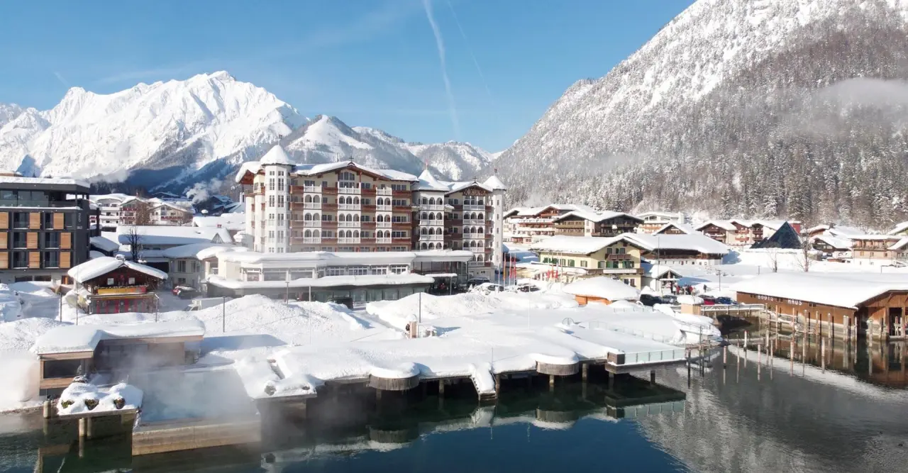 Winterpanorama des Hotel Entners am See mit beheiztem Aussenpool direkt am Achensee und schneebedeckten Bergen.