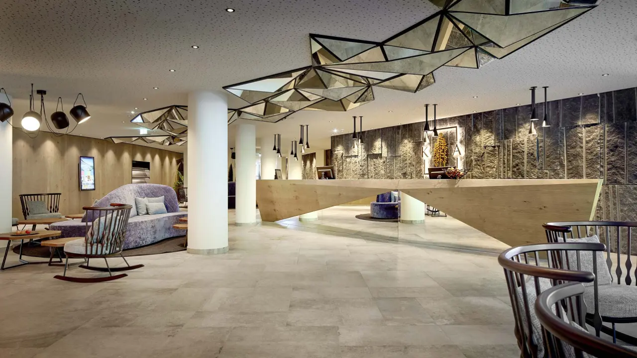 Moderne und elegante Hotellobby des Krumers Alpin – Your Mountain Oasis****s mit Rezeption und Sitzbereichen.