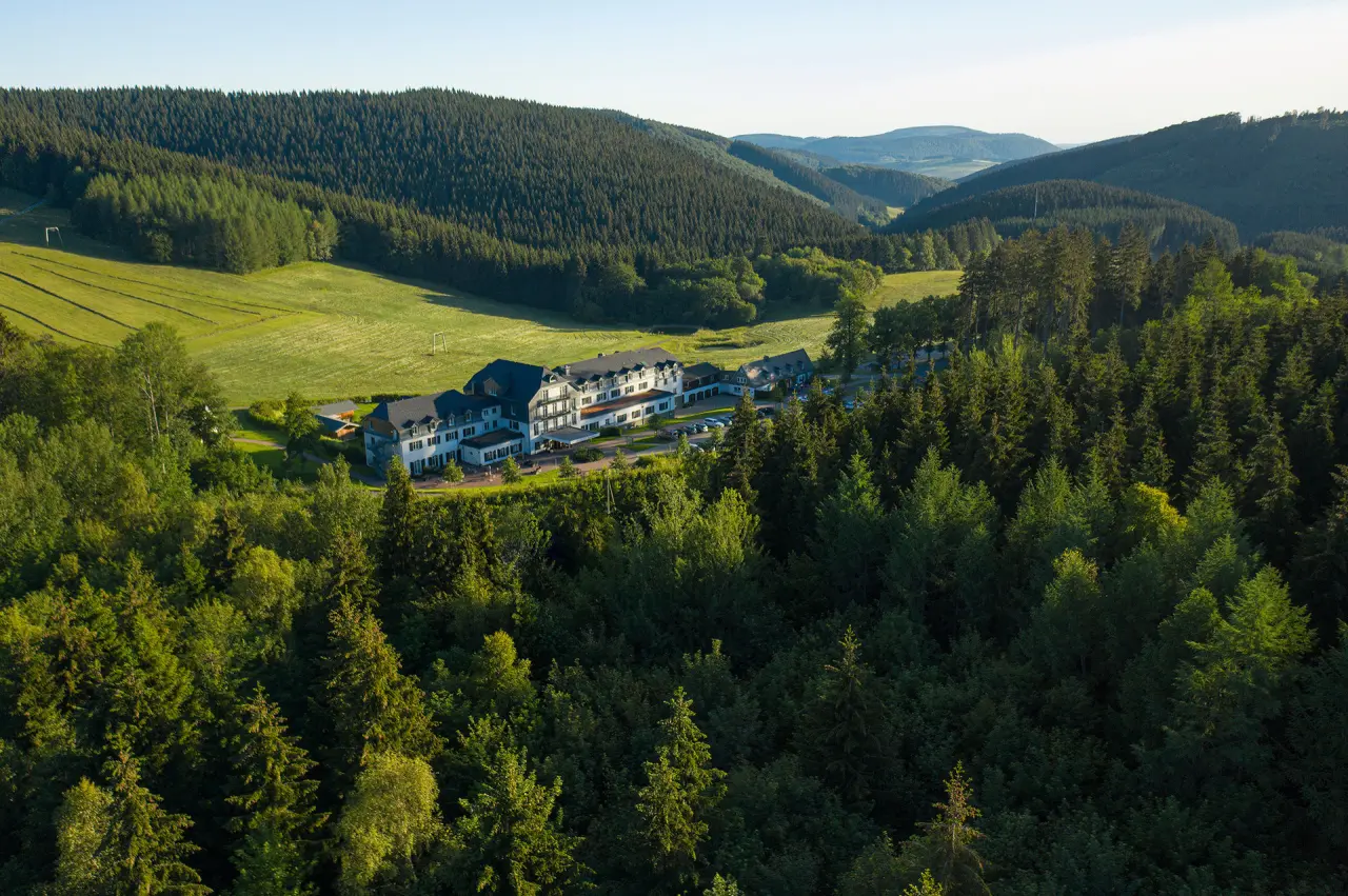 Panoramablick auf das Hotel Rimberg, eingebettet in grüne Wälder und Wiesen im idyllischen Sauerland.