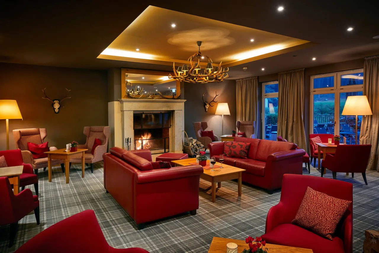 Gemütliche Hotellobby mit knisterndem Kamin, roten Ledersofas und warmem Licht im Hotel Rimberg.