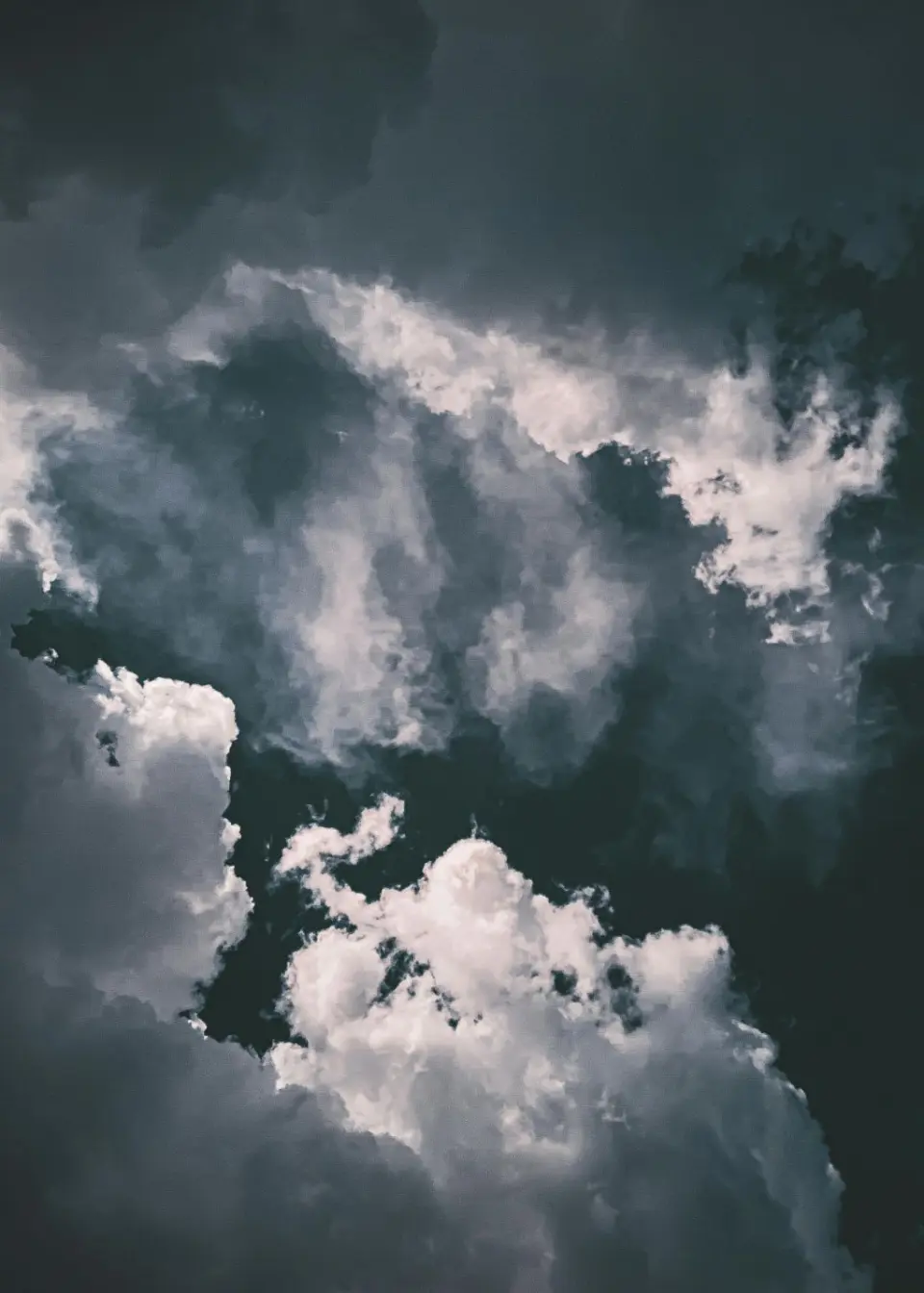 Dunkle, dramatische Wolkenformationen am Himmel mit hellen Lichtblicken.