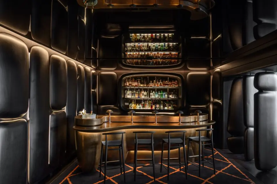 Elegante Hotelbar mit beleuchteten Spirituosenregalen und Messingtheke im The Dolder Grand.