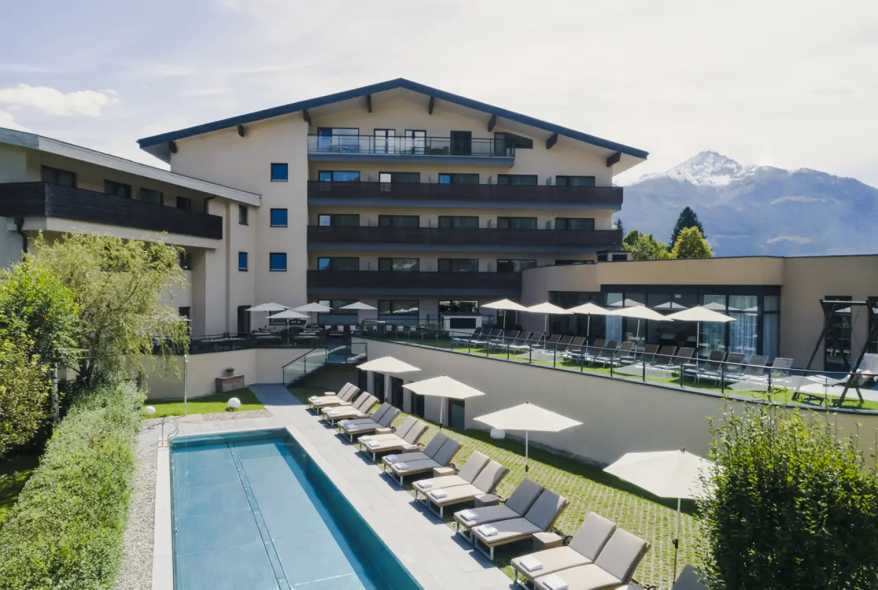 Aussenansicht des HAIDVOGL MAVIDA Zell am See mit Aussenpool und Liegewiese vor Bergpanorama.
