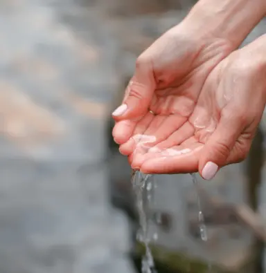 Hände schöpfen frisches Wasser, symbolisch für Reinheit und Wellness im Parkhotel Bad Füssing.