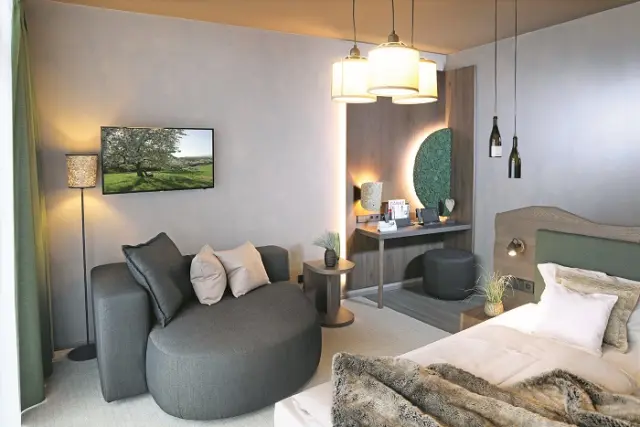 Modernes Hotelzimmer im Schwarzwald Panorama mit Doppelbett, gemütlicher Sitzecke und Schreibtisch.