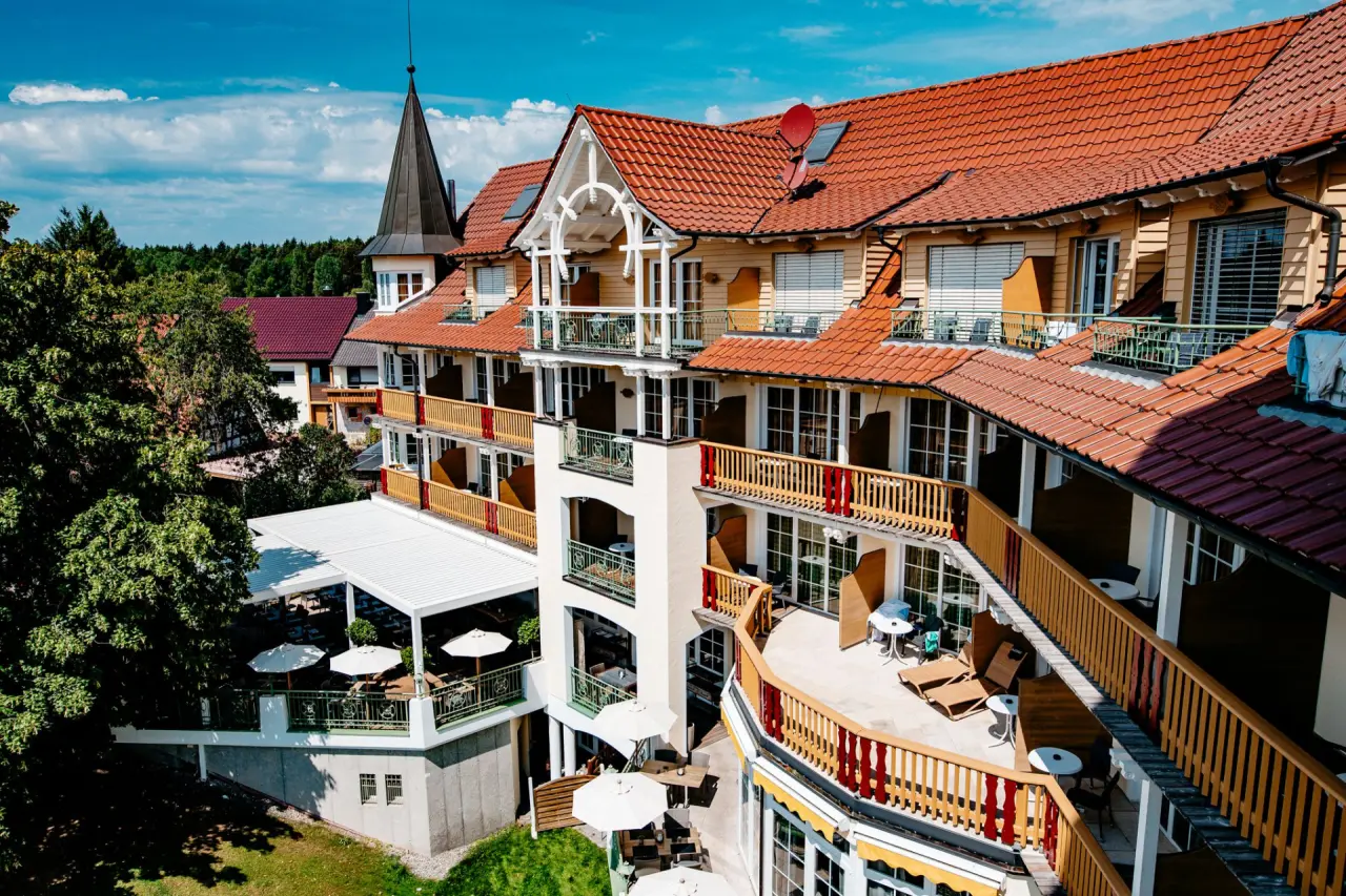 Panoramablick auf das Meiser Vital Hotel mit seinen charakteristischen roten Dächern und Balkonen, umgeben von Grün unter blauem Himmel.