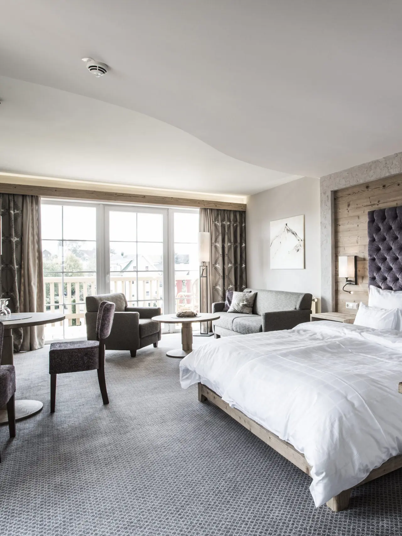 Helles, geräumiges Hotelzimmer im Meiser Vital Hotel mit Doppelbett, gemütlichem Sitzbereich und Balkon.