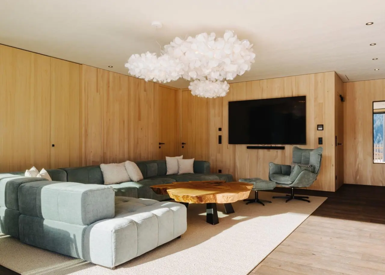 Modernes Wohnzimmer einer Suite im Torghele's Wald & Fluh mit Holzvertäfelung, großem Sofa und Bergblick.