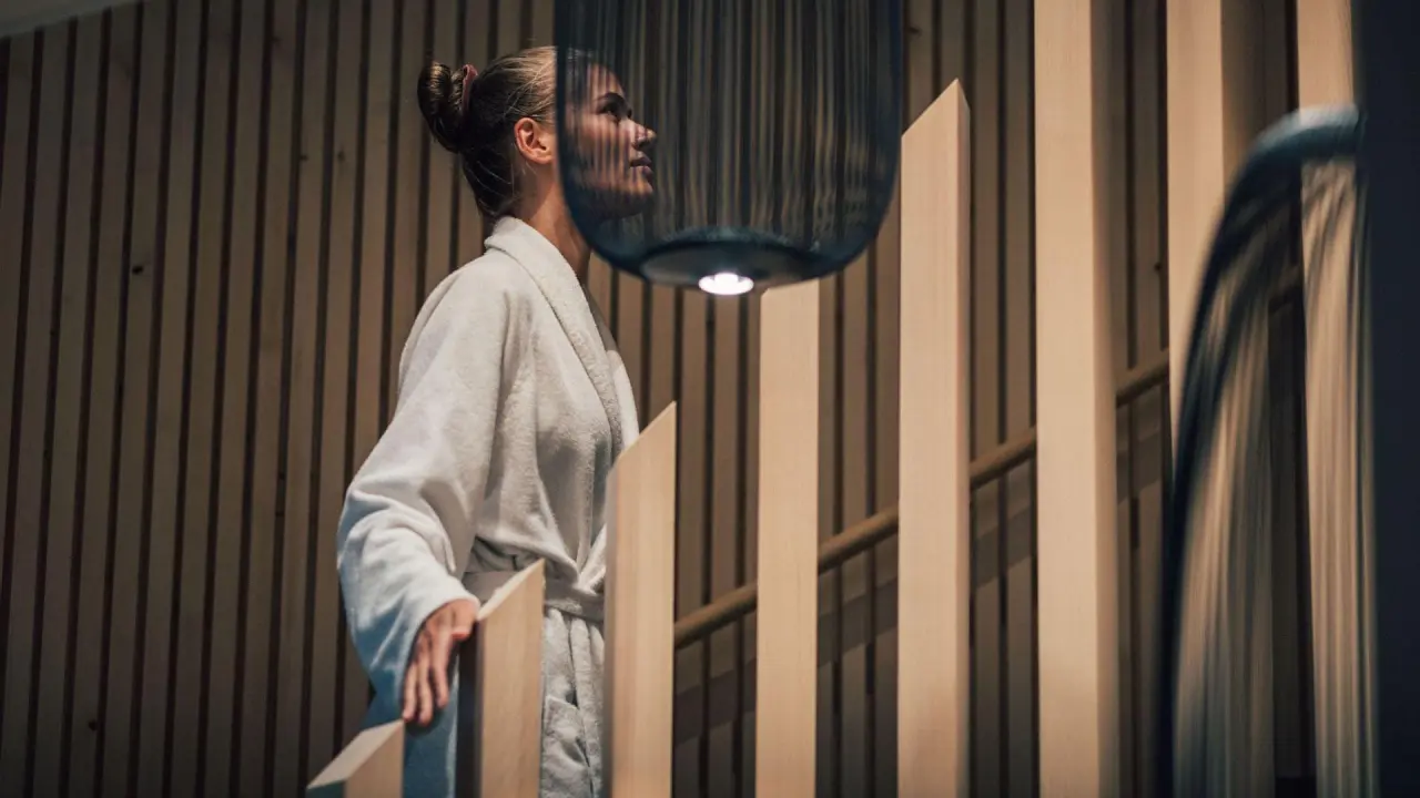 Frau im Bademantel auf einer Holztreppe im modernen Spa-Bereich des Torghele's Wald & Fluh Hotels.