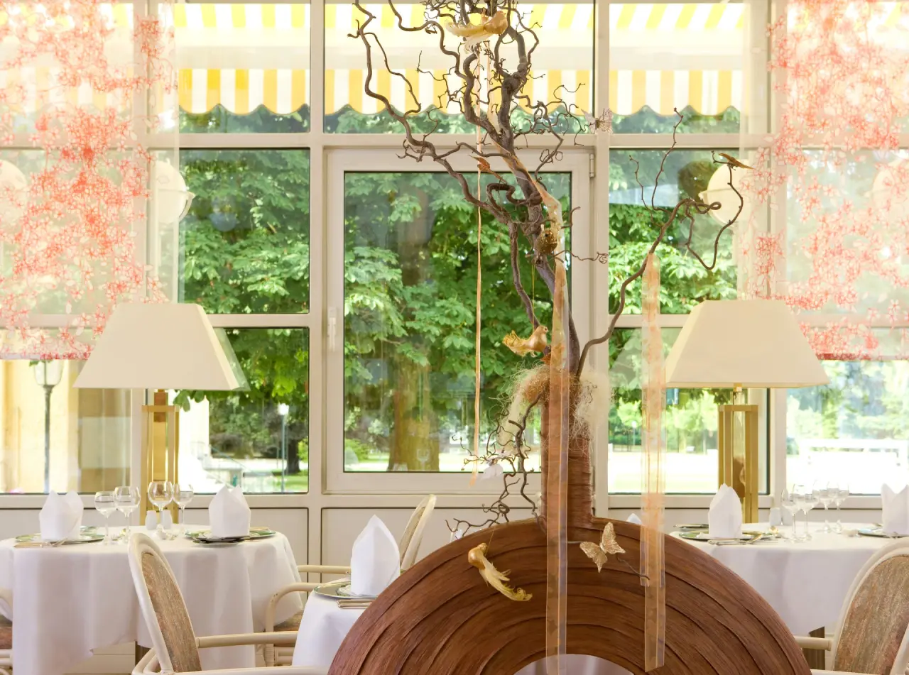 Elegantes Restaurant im Steigenberger Bad Pyrmont mit Blick ins Grüne und festlich gedeckten Tischen.