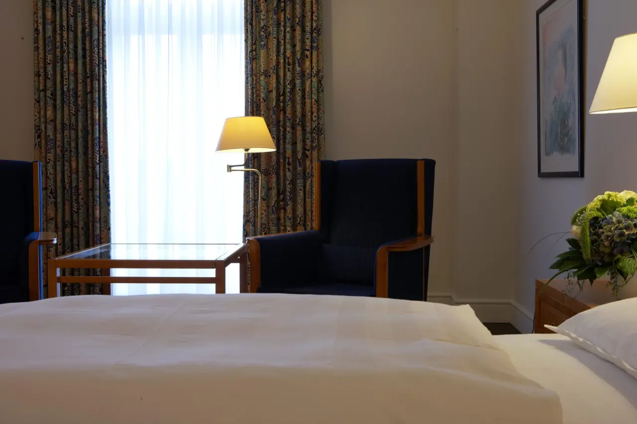 Gemütliches Hotelzimmer im Steigenberger Bad Pyrmont mit Sessel, Tisch und Blick zum Fenster.