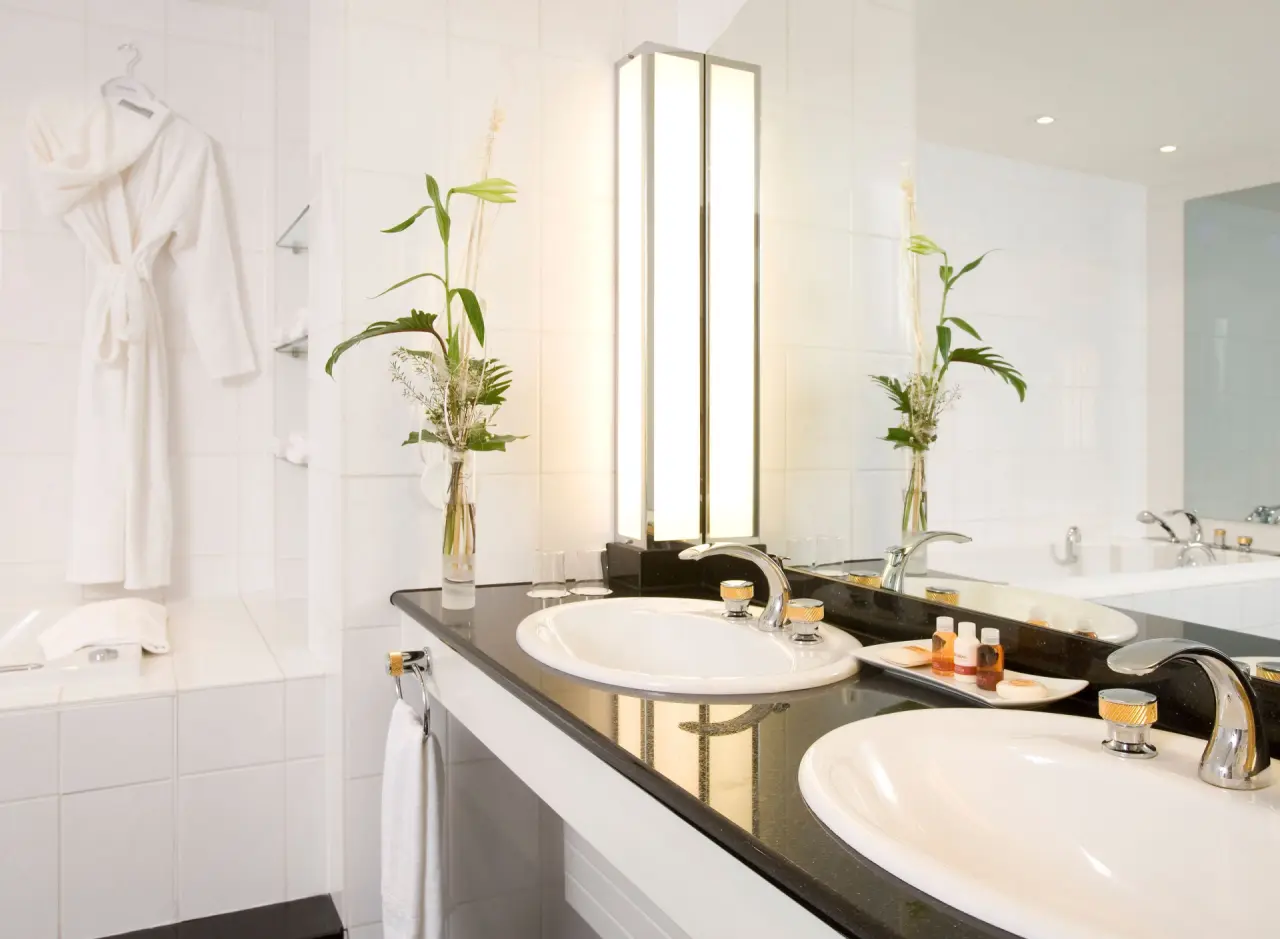 Modernes Badezimmer mit Doppelwaschbecken, Badewanne und Bademantel im Steigenberger Hotel Bad Pyrmont.