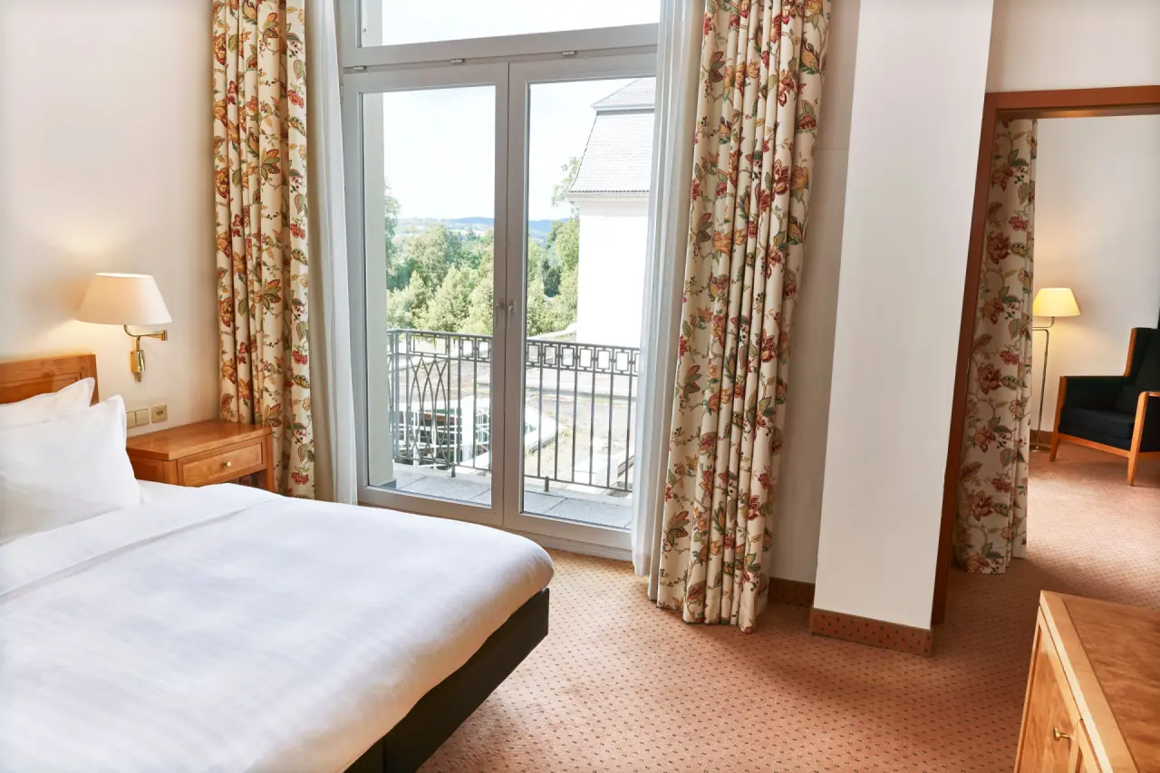 Gemütliches Hotelzimmer mit Doppelbett, Balkon und Blick ins Grüne im Steigenberger Bad Pyrmont.