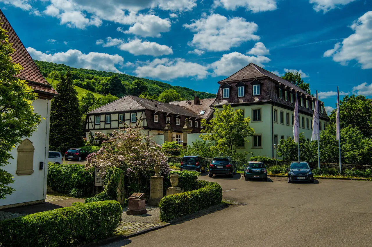 Aussenansicht des Schloss Döttingen mit historischen Gebäuden, grünen Hügeln und blauem Himmel an einem sonnigen Tag.