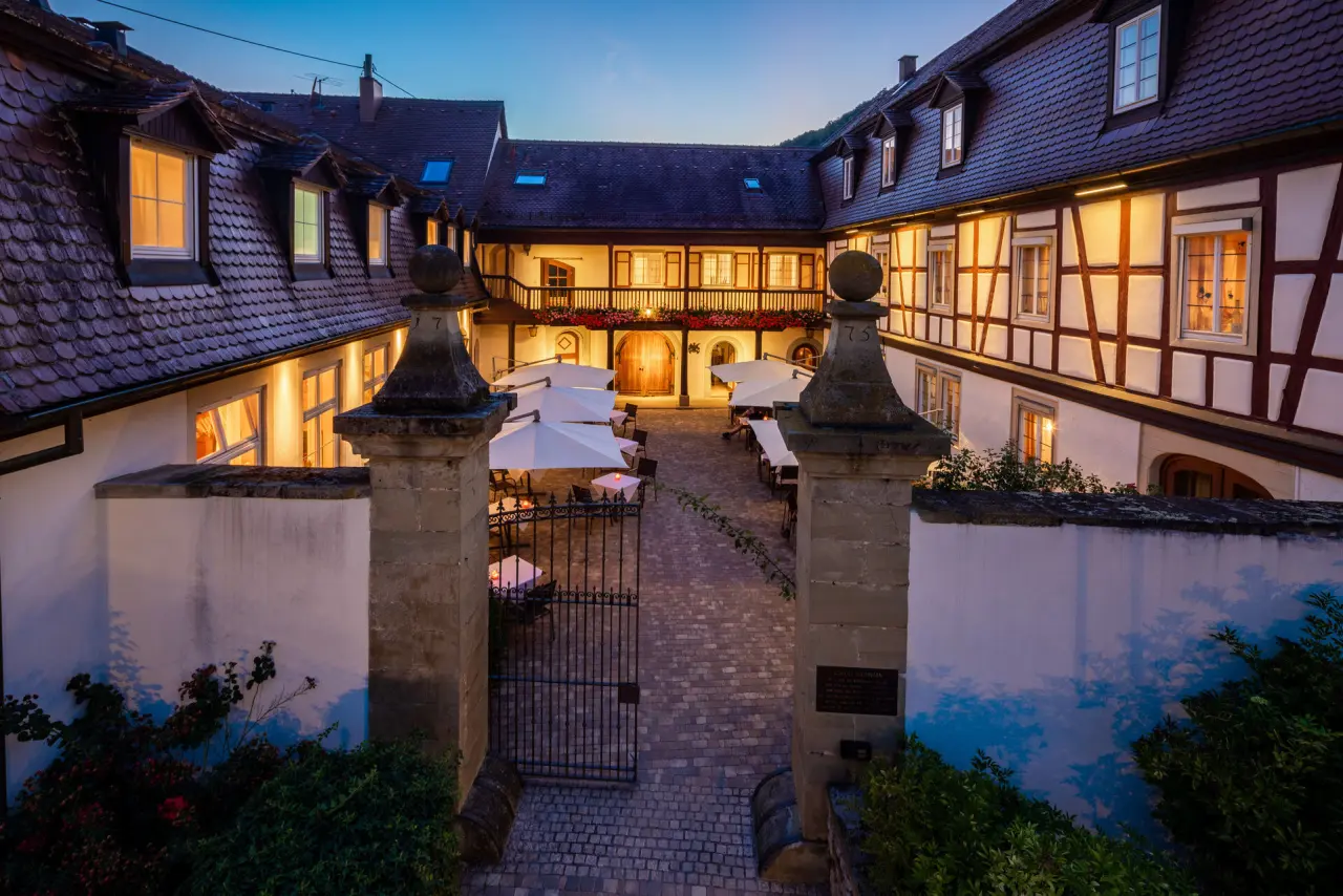 Abendliche Ansicht des historischen Schloss Döttingen mit beleuchtetem Innenhof, Restaurant-Tischen und Fachwerkfassaden.
