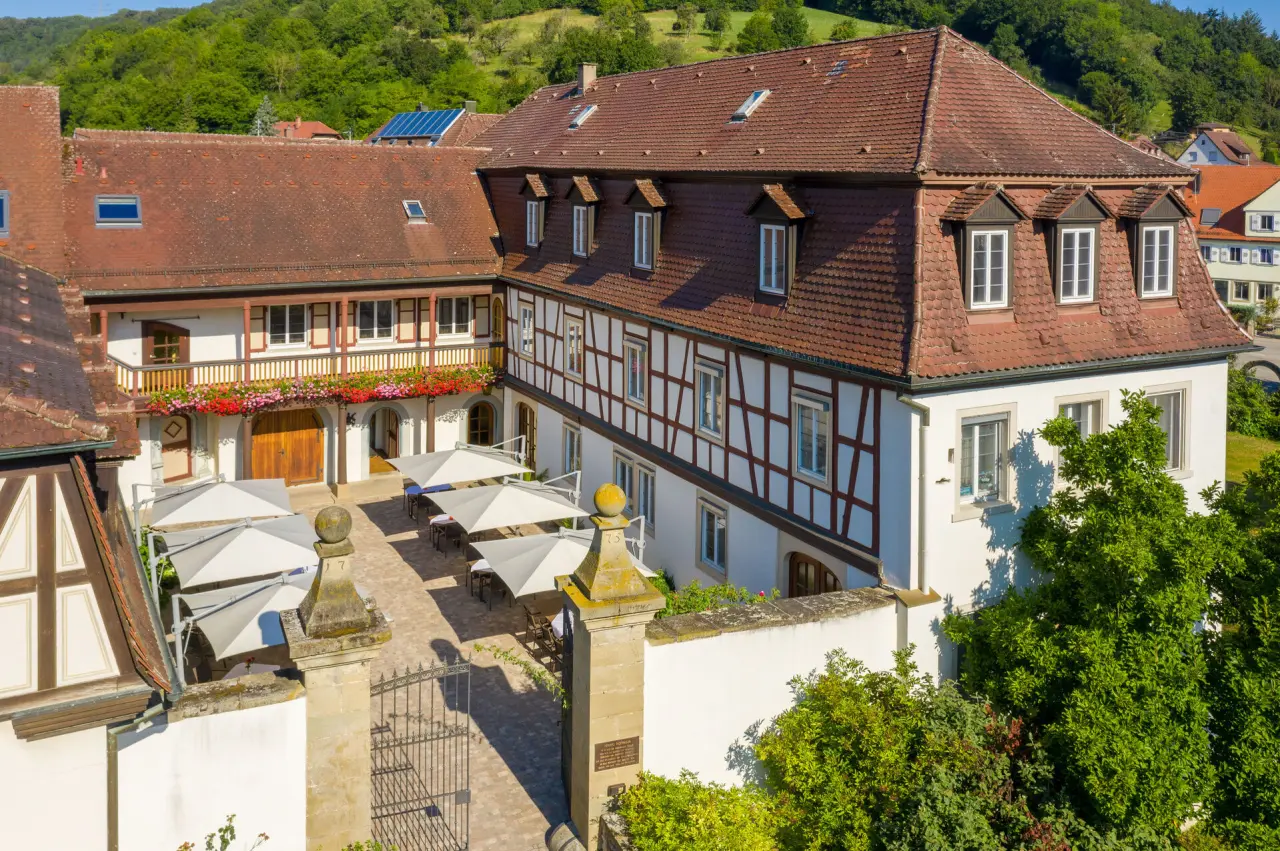 Historisches Schloss Döttingen Hotel mit Fachwerkhof, blühenden Balkonen und sonniger Terrasse im Grünen.