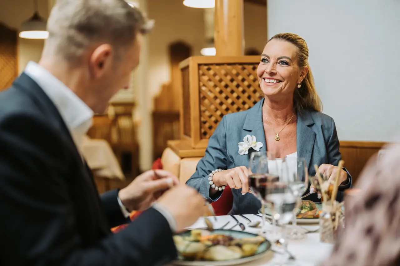 Lachende Gäste genießen ein Abendessen im eleganten Restaurant des Kurhotel Sonnenhof. Kulinarische Erlebnisse im Wellnesshotel.