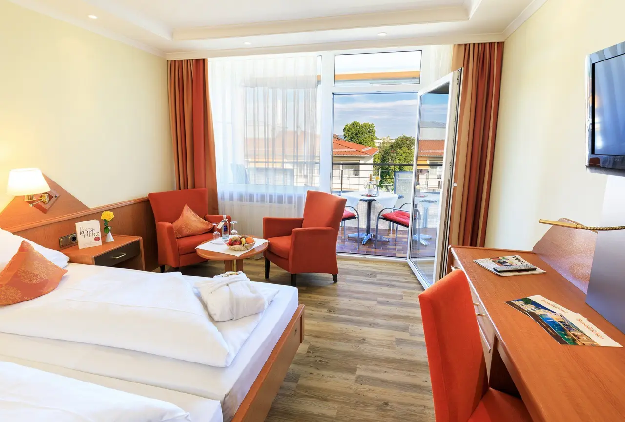 Helles, komfortables Hotelzimmer im Kurhotel Sonnenhof mit Doppelbett, Sitzbereich, Schreibtisch und Balkon.