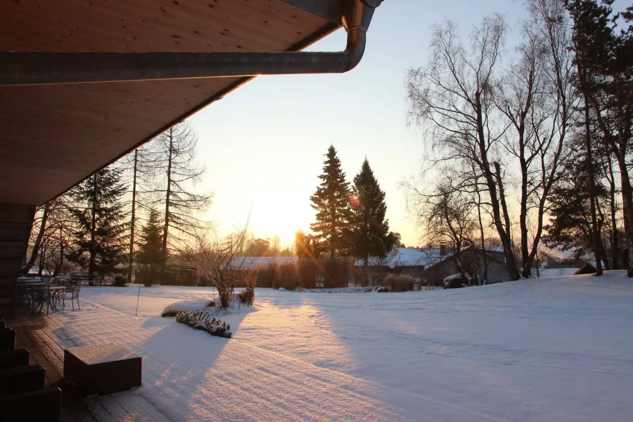 Verschneiter Hotelgarten des Gesundheitshotels Klosterberg bei Sonnenuntergang im Winter.