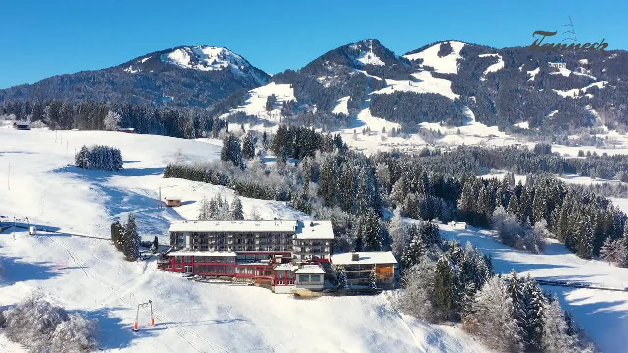 Winterliche Aussenansicht des Hotel Allgäu Tanneck mit verschneiten Bergen und Skipisten im Allgäu.