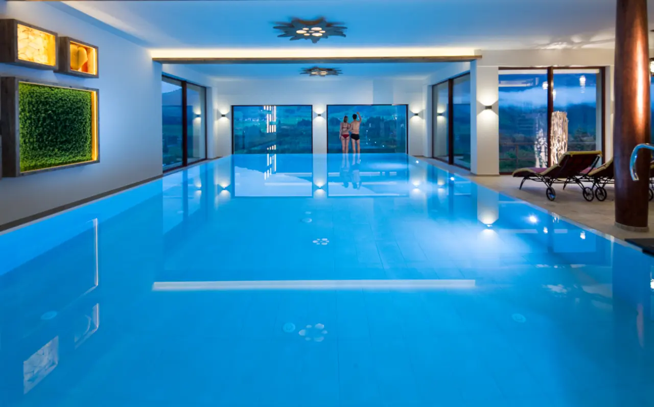 Beheizter Innenpool mit Panoramablick und entspannenden Liegen im Wellnessbereich des Hotel Allgäu Tanneck.