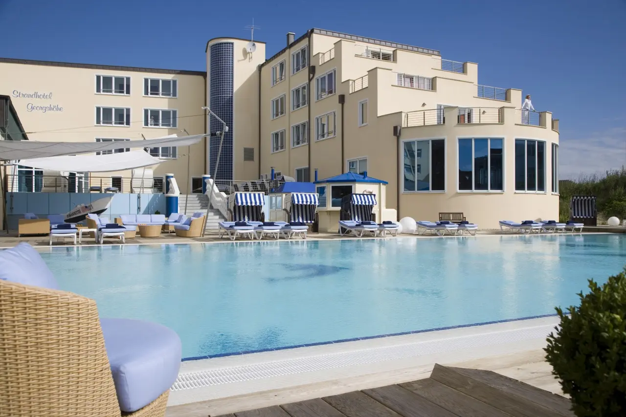 Sonniger Aussenpool mit Liegen und Strandkörben vor dem Strandhotel Georgshöhe. Ideal für Entspannung.