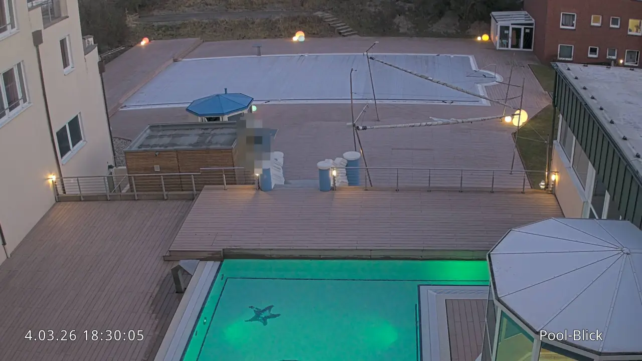 Abendlicher Blick auf den beleuchteten Aussenpool mit Seestern-Mosaik im Strandhotel Georgshöhe. Ein weiterer Pool ist abgedeckt.