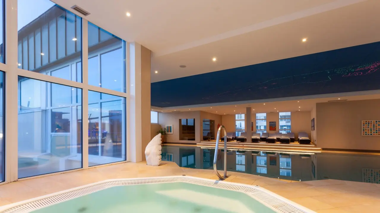 Grosszügiger Innenpool mit Whirlpool und grossen Fenstern im Wellnessbereich des Strandhotel Georgshöhe.