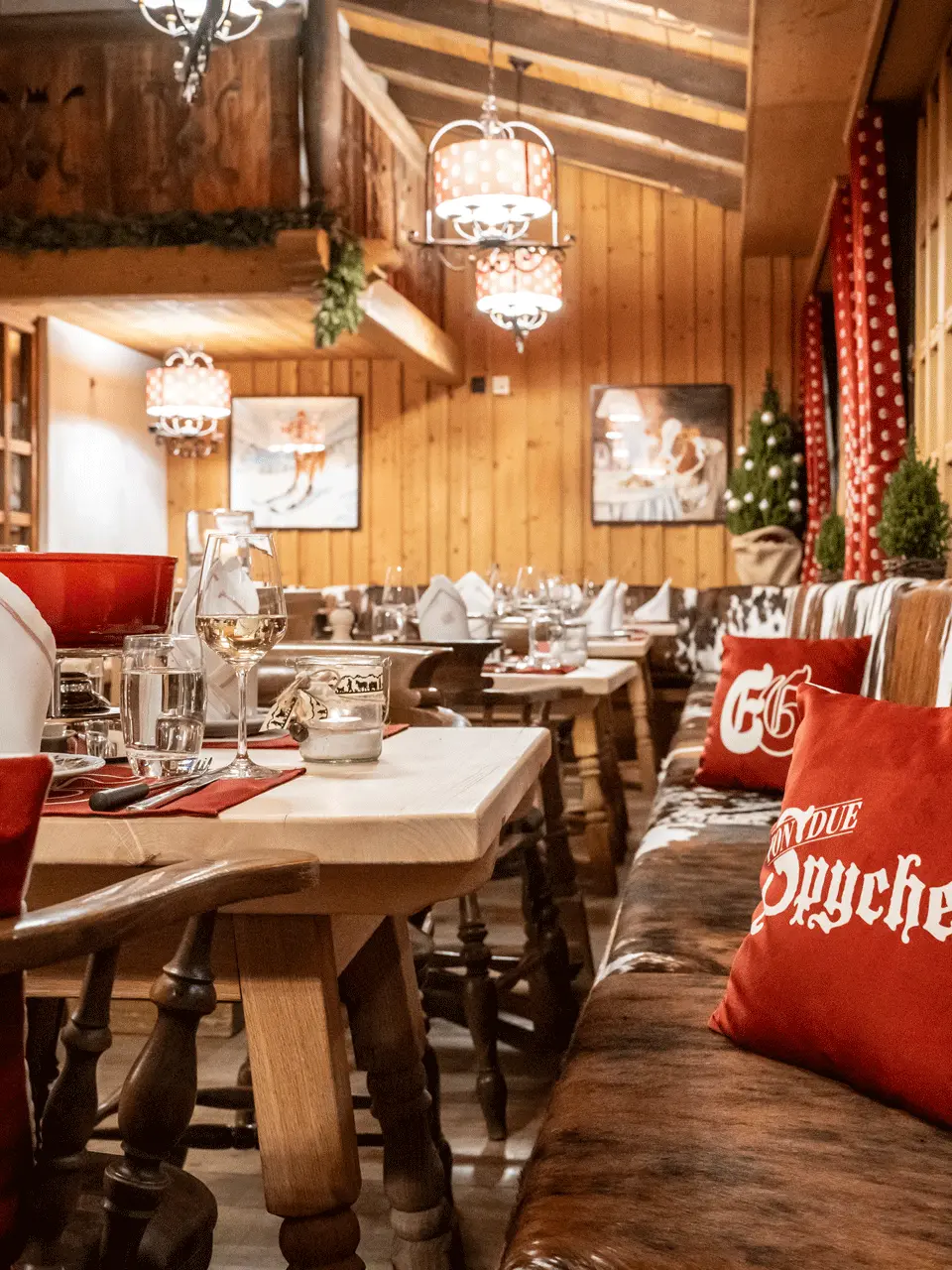 Gemütliches Restaurant im Chalet-Stil mit Holztischen, Kuhfell-Bänken und festlicher Dekoration im ERMITAGE Wellness- & Spa-Hotel.