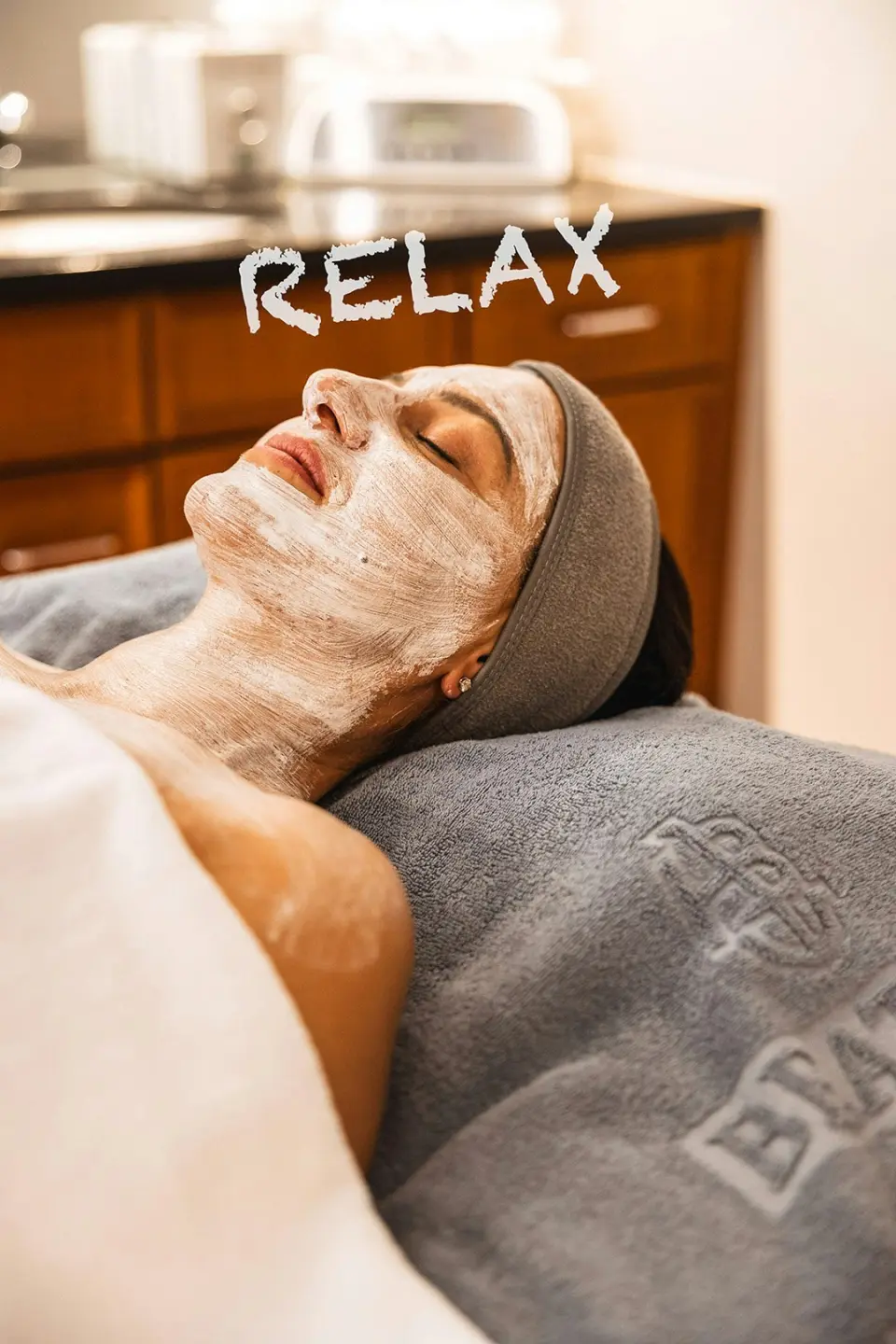 Frau mit Gesichtsmaske entspannt bei einer Wellness-Behandlung im Spa-Bereich des ERMITAGE Wellness- & Spa-Hotels.