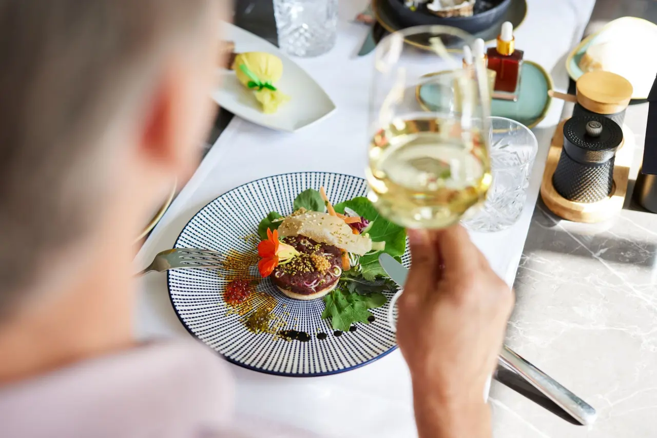 Exquisit angerichtetes Gericht mit Wein im Restaurant des Strandhotel Zingst. Kulinarischer Genuss.