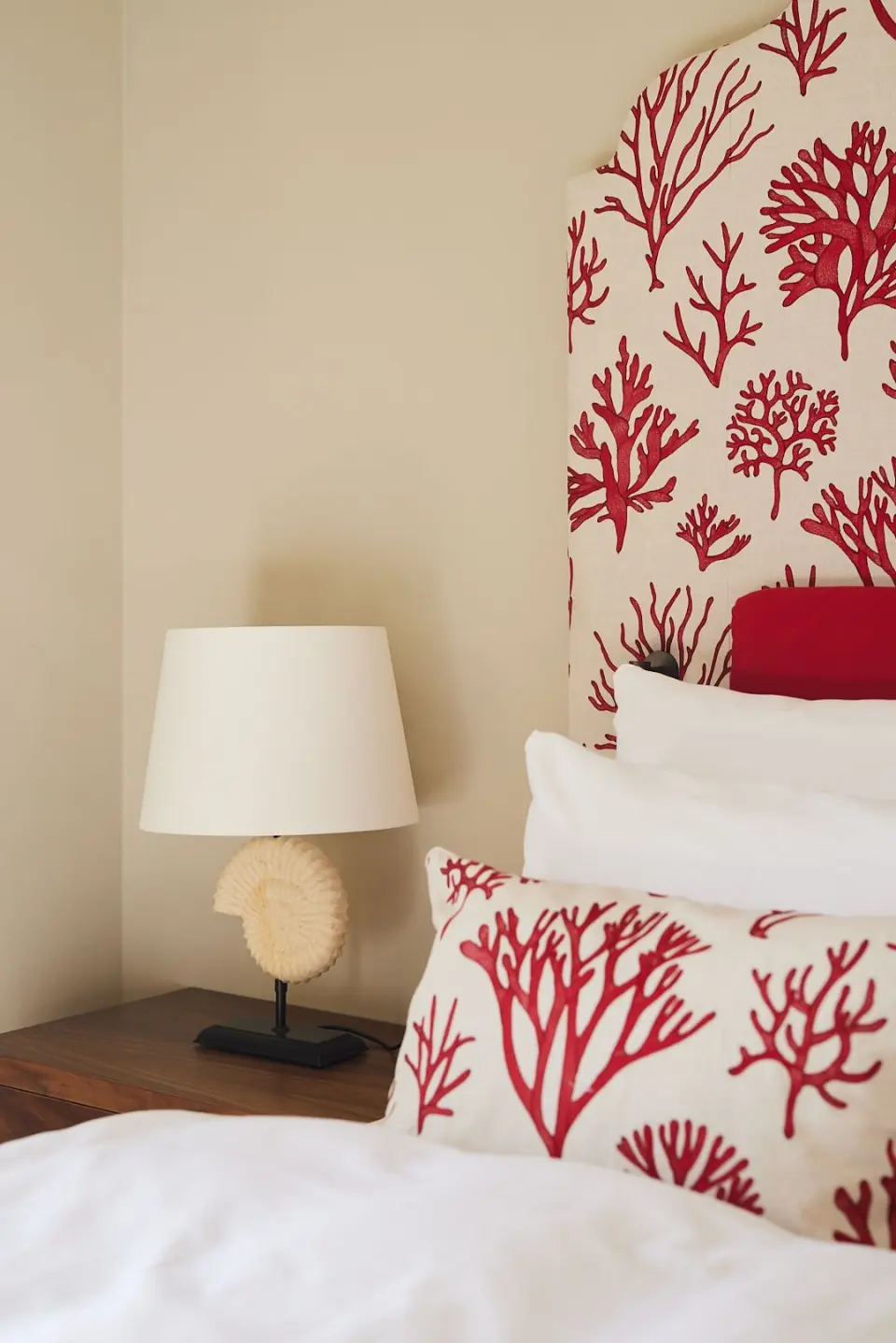 Detailaufnahme eines Hotelzimmers im Strandhotel Zingst mit Korallenmuster auf Kissen und Kopfteil sowie einer Muschellampe.