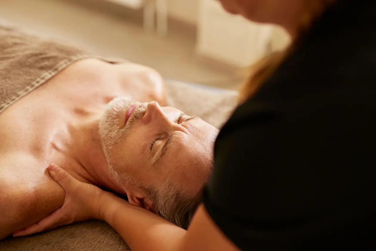 Mann genießt entspannende Nackenmassage im luxuriösen Spa des Strandhotel Zingst.
