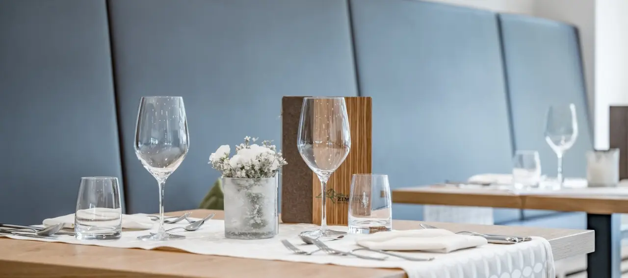 Gedeckter Tisch im Restaurant des Alpenhotel Zimba mit Gläsern, Besteck und Blumendeko.