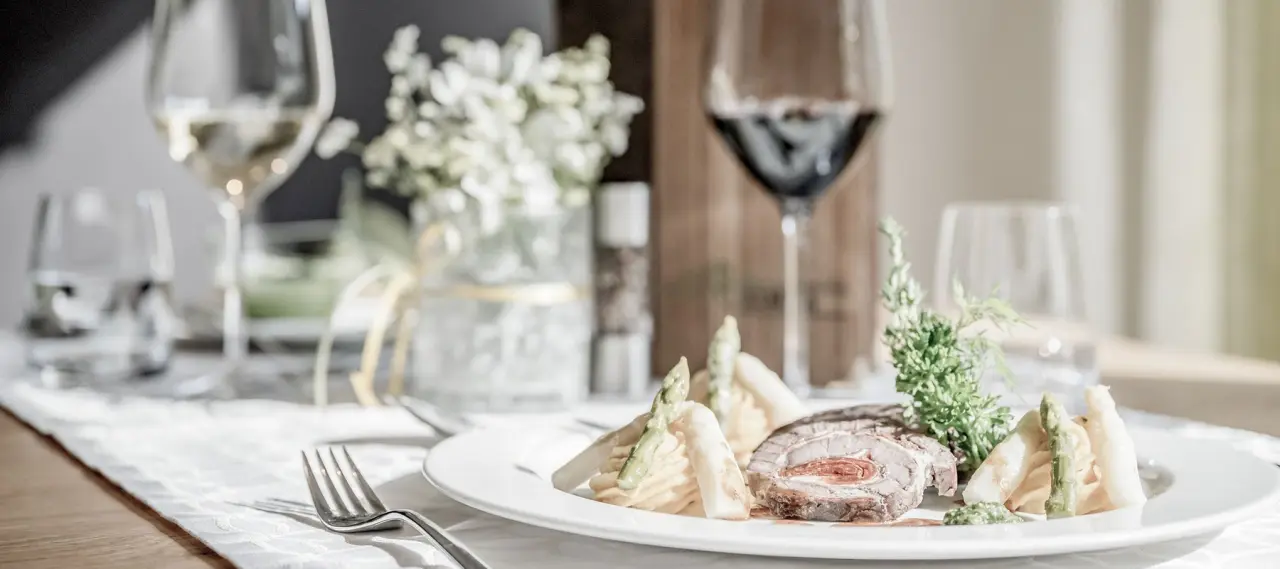 Exquisites Abendessen mit Fleischroulade, Spargel und Wein im Restaurant des Alpenhotel Zimba.